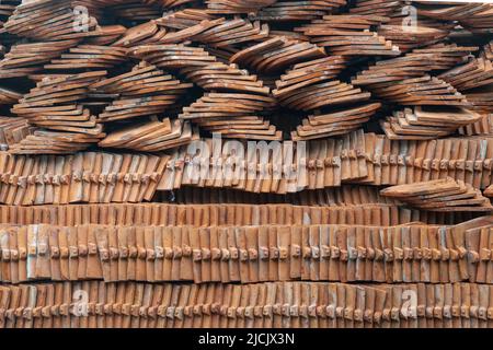 Pile or stack of traditional glazed clay roof tiles used for covering rooftop of Thai buddhist temples restoration. Typical of Asia construction, Sele Stock Photo