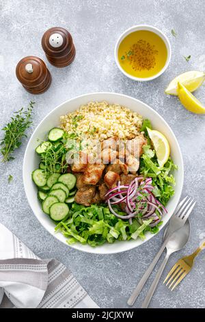 Pork kebab bulgur salad bowl with cucumber, lettuce, thyme and mustard sauce Stock Photo