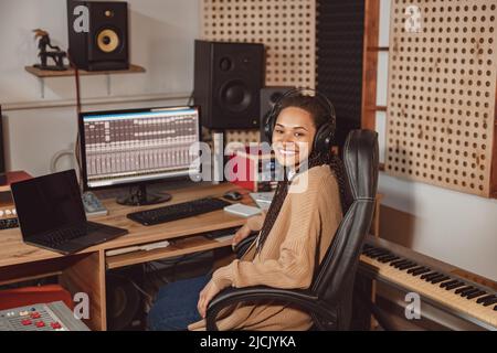 Beautiful stylish African woman audio engineer, musician and producer working in music recording studio soundproof room Stock Photo