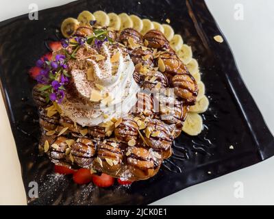 Hong Kong style egg waffle with strawberry, banana, and whipped cream Stock Photo