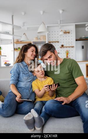 Happy family using digital technology decives for playing watching movies, relaxing at home. Stock Photo