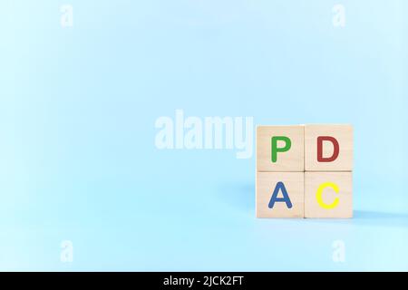 PDCA or Plan Do Check Act cycle method concept. Hand putting action wooden blocks in blue background with copy space. Stock Photo