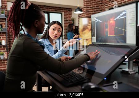 Videogame developing company employees working on alpha build of 3D game project while sitting at desk. Production department diverse team members optimising digital product using modern software. Stock Photo