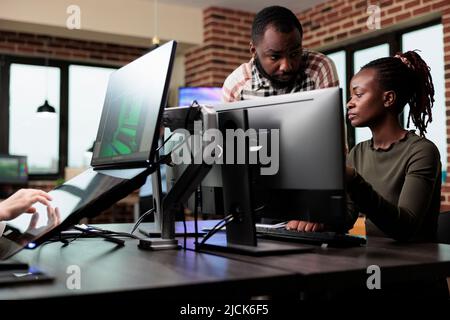 Creative african american office workers discussing about 3D project development progress. Diverse colleagues conversating about professional digital art while sitting at desk in workspace. Stock Photo
