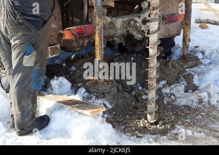 Water well drilling rig in operation, close up view, man controlling Stock Photo
