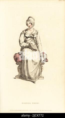 Regency woman in morning dress and mob cap reading a book. In French jacket and petticoat of cambric muslin, French mob cap of satin and quilled lace. Vol. 14, Plate 27, November 1, 1815. Handcoloured copperplate engraving by Thomas Uwins from Rudolph Ackermann's Repository of Arts, Strand, London. Stock Photo