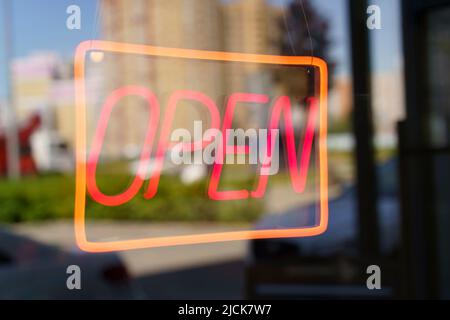 Neon sign open on the glass door of a shop or cafe. Selected focus. High quality photo Stock Photo