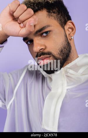 portrait of bearded and young african american man with blue eyes isolated on purple Stock Photo