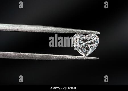 Oval shape diamond with tweezers on black background Stock Photo
