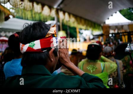 Rear view of hindu people praying while holding flowers in their hands Stock Photo