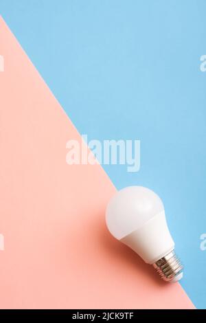 White economy light bulb on blue and pink background. Stock Photo