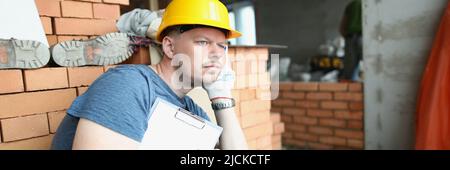Upset worker sit surrounded with construction site mess with paper Stock Photo