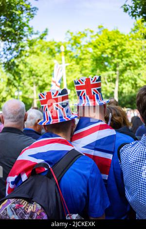 Couple wearing union jack flags and hats on The Mall in London, England. The Platinum Jubilee of Queen Elizabeth II is being celebrated in 2022 Stock Photo