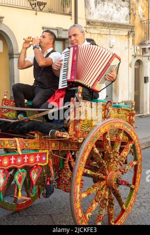 Traditional Sicilian folk musicians with their gaily decorated horse and cart - a 'carrettu sicilianu' - at a local festival in Maletto, Sicily Stock Photo