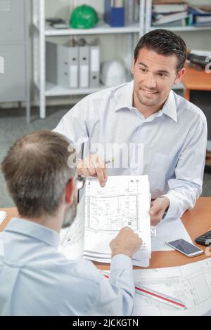 Two men in meeting looking at blueprints Stock Photo