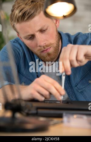young male engineer repairs a laptop Stock Photo