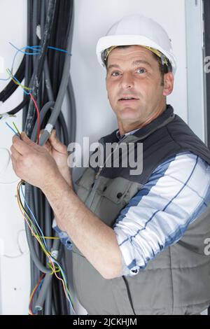electrician fitting wiring on construction site Stock Photo