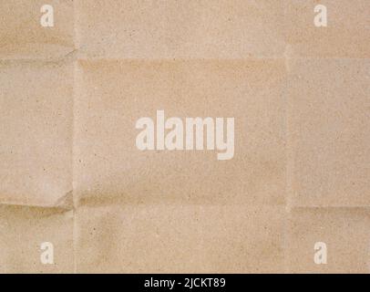 The surface of beige wrapping craft paper with wrinkled lines and shadows. Empty texture sheet of cardboard from recycled material with a fold pattern Stock Photo