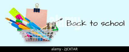 The shopping cart is filled with office supplies. Back to school, education concept on blue background. Mini basket with pencils, felt-tip pens. Stock Photo