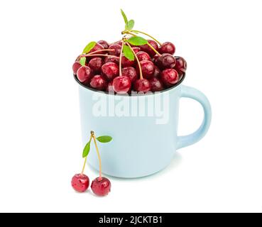 Red ripe cherry in a blue mug on a white background. Sweet berries, delicious dessert in a cup, healthy summer seasonal fruits, harvest. Stock Photo