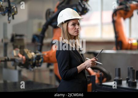 Portrait of female chief engineer in modern industrial factory using tablet. Stock Photo