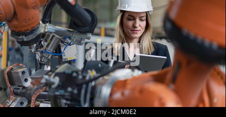 Portrait of female chief engineer in modern industrial factory using tablet. Stock Photo