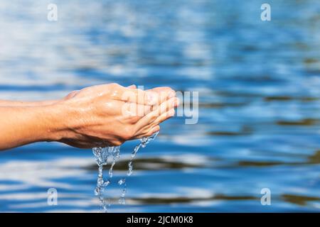 Person scoops up raw water from a lake. Natural water resources environmental awareness concept Stock Photo