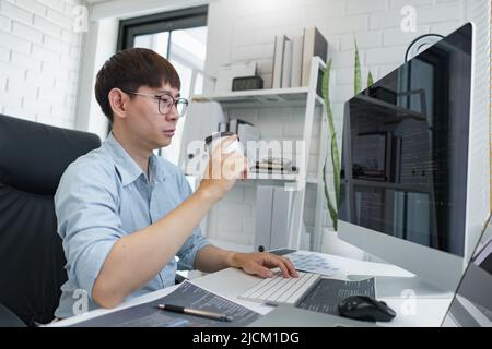 Software development concept, Male programmer checking website programming and drinking coffee. Stock Photo