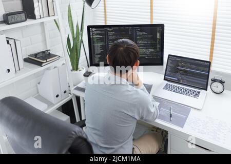 Software development concept, Male programmer typing data code and working on multiple screens. Stock Photo