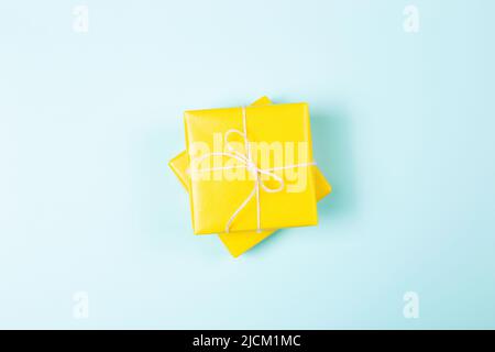 Two yellow packed square gift boxes on pastel blue background. Flat lay. Minimal style. Holiday concept. Stock Photo