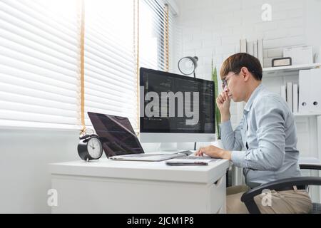 Software development concept, Male programmer looking data on laptop and typing codes on keyboard. Stock Photo