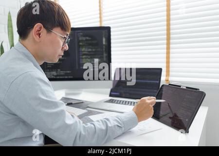 Software development concept, Male programmer point data on tablet to checking website programming. Stock Photo