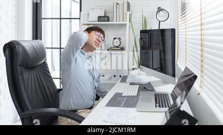 Software development concept, Male programmer suffering neck pain after working hard on computer. Stock Photo