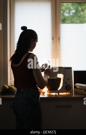 Housewife woman baking at home using kitchen planetary mixer in a cozy kitchen Stock Photo