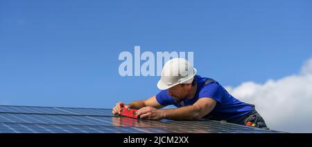 Man worker installing solar photovoltaic panels on roof, alternative energy concept. Stock Photo