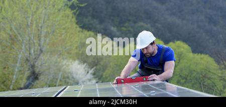 Man worker installing solar photovoltaic panels on roof, alternative energy concept. Stock Photo
