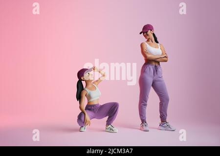 Happy young woman smiling at her metaverse avatar in a studio. Cheerful young woman standing next to the 3D simulation of herself. sporty young woman Stock Photo
