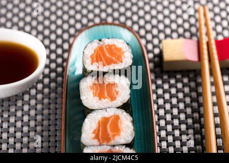 Top down view of gourmet Hosomaki salmon sushi rolls with rice and Nori seaweed served on an oblong platter at a sushi bar or restaurant with chopstic Stock Photo