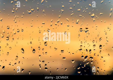 Raindrops on a window with a sunset sky in the background. Clear weather after the rain. Stock Photo