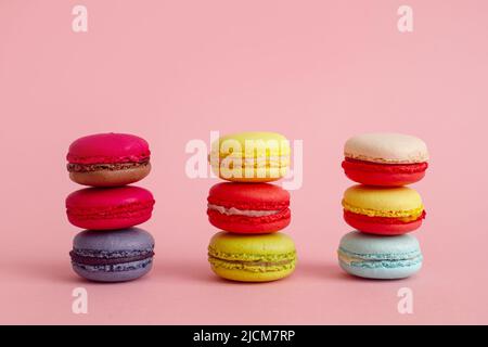 Three stacks of colourful french macaroons or macaron on pink background, Dessert, confectionery, biscuit macaroons with layer of filling. Isolated on Stock Photo
