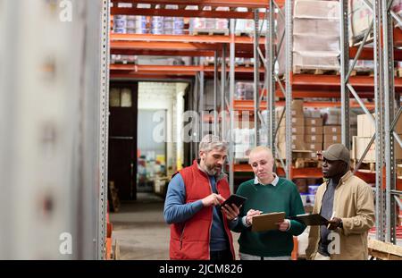 Group of workers working in team in warehouse using digital tablet and distributing transportation of cargo Stock Photo
