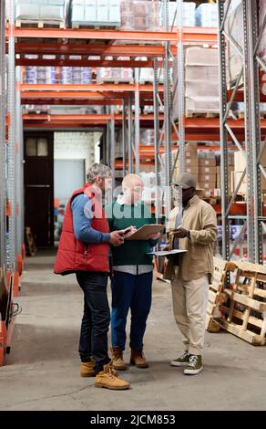 Warehouse workers discussing shipping with supervisor during their work in warehouse Stock Photo