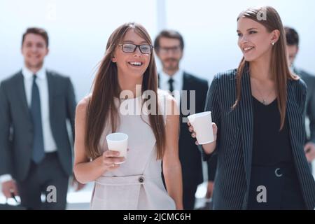 employees with cups of coffee discussing something during a work break Stock Photo