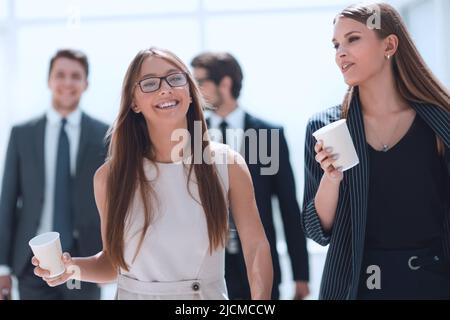 employees with cups of coffee discussing something during a work break Stock Photo
