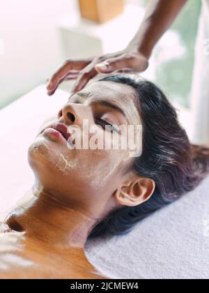 A young woman receives a Nourishing Pink Clay Facial treatment at a spa. Stock Photo