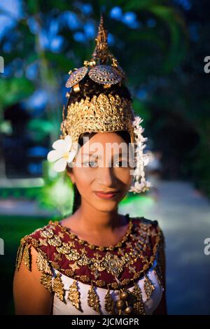 A young Cambodian Apsara dancer walks on a pathway at dusk. Siem Reap, Cambodia. An Apsara dancer is a classical Khmer dancer. Stock Photo