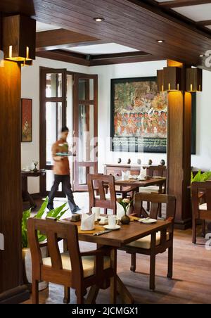 Young Asian server sets up tables in a hotel restaurant. Siem Reap, Cambodia. Stock Photo