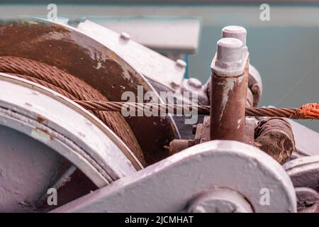 close-up of an old large winch with a rusty cable wound around it. Stock Photo