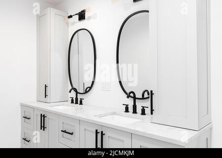 A luxury bathroom with a grey double vanity cabinet, black faucets and lights, and a white marble countertop. Stock Photo
