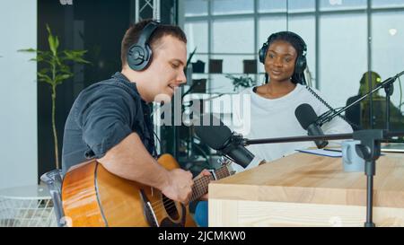 An Influential Musician Sings and Plays the Guitar During a Radio Broadcast in the Studio. Online Radio Concept. Stock Photo